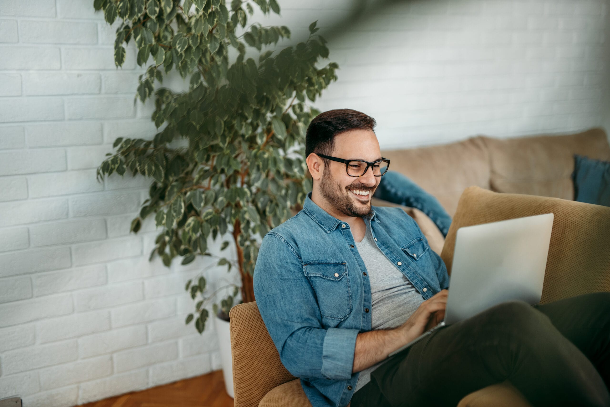 Portrait of a cheerful man using laptop at home.