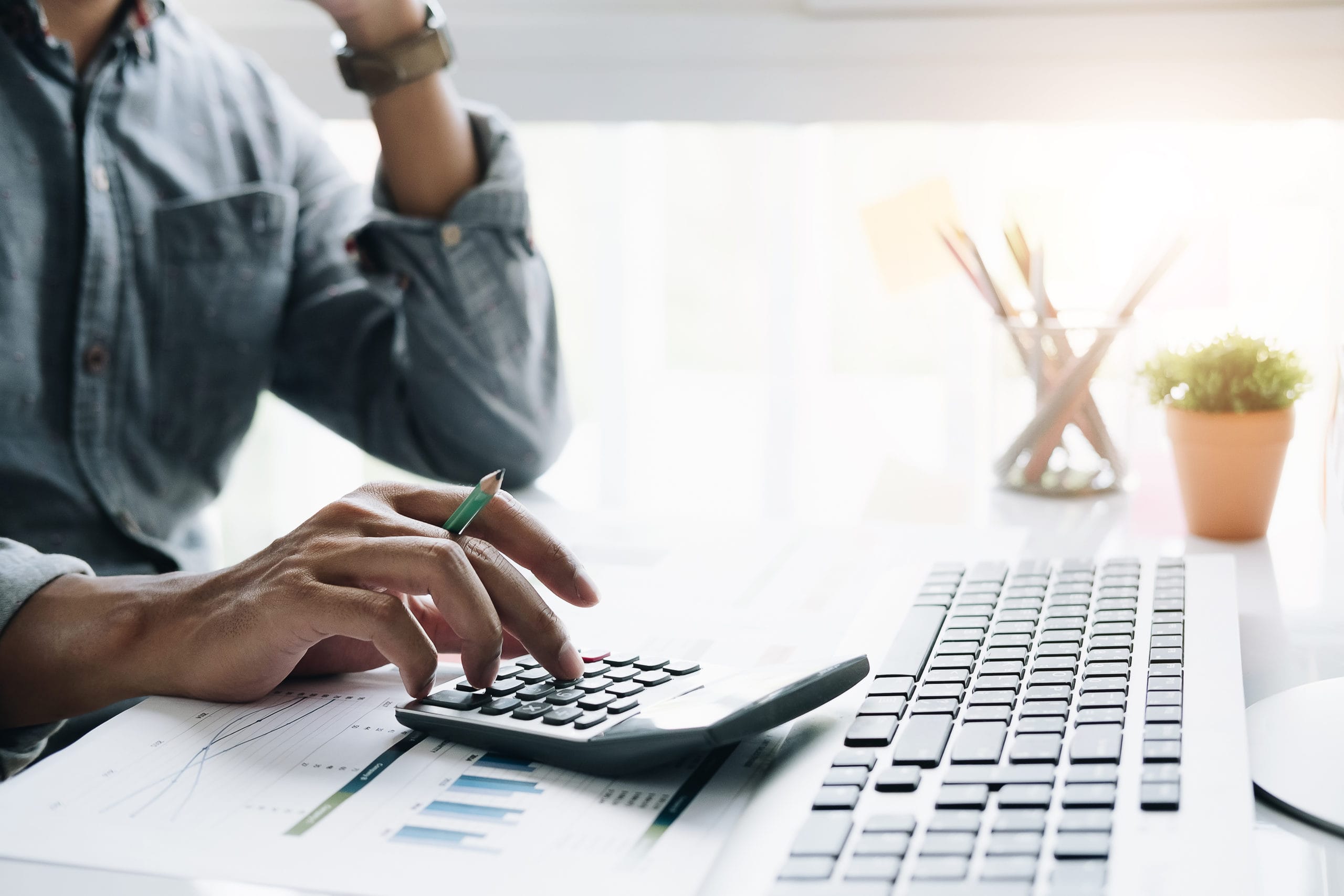 Closeup of a businessman financial specialist is working with calculator and computer to analyze a lot of data on financial report